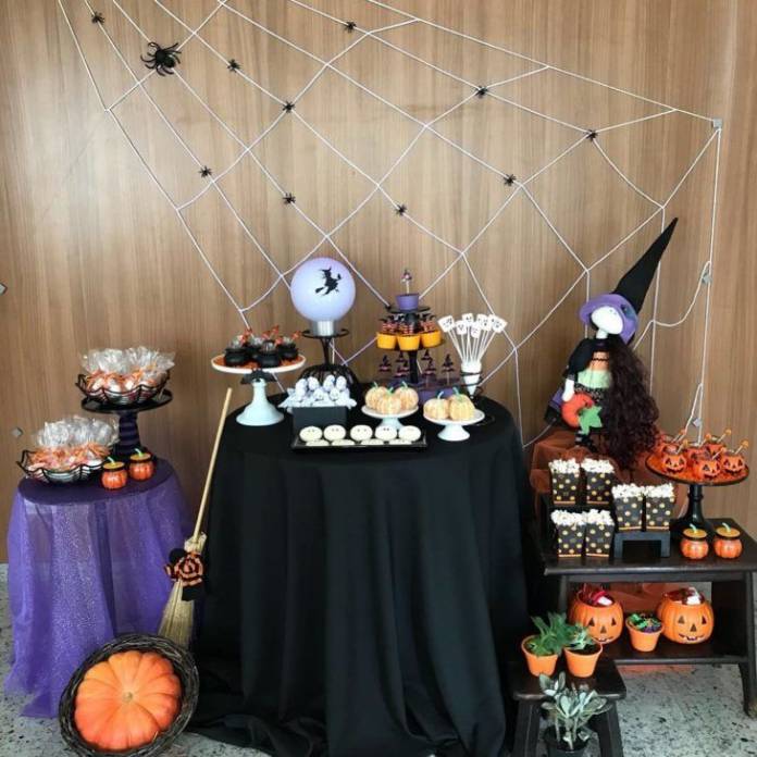 mesa decorada com tema do halloween com aboboras de plastico e bruxas 