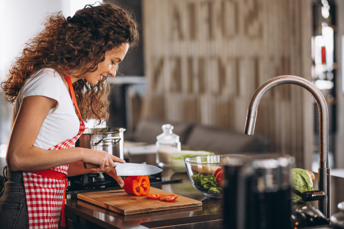 Mulher cozinhando depois de solicitar o auxílio gás. 