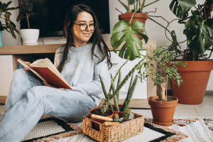 mulher com várias plantas em casa usando o estilo Urban Jungle para decoração.