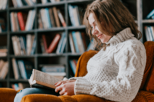 mulher sentada e lendo em sua biblioteca em casa.