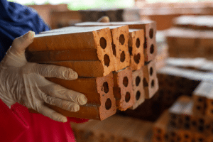 profissional segurando tijolos ao entender como comprar materiais de construção.