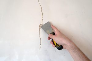 Pessoa consertando rachadura em parede ao descobrir como fazer