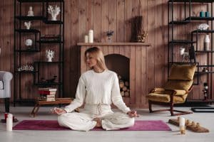 Mulher meditando e cuidando de si e seguindo tendências de decoração para 2024.