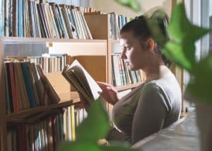 Mulher lendo livro ao entender como criar um cantinho da leitura em casa.