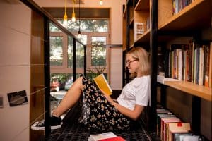 Mulher lendo ao descobrir Como criar um cantinho da leitura e fazer um espaço com estantes em casa.