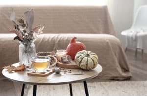 Sala de estar com decoração de outono, com velas, flores e mantas.