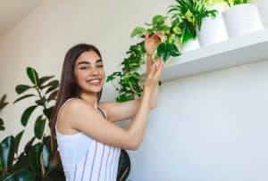 Mulher feliz com plantas para apartamento.