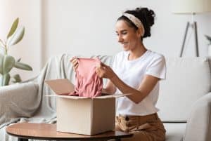 Happy young woman opening carton box, checking delivery, copy space