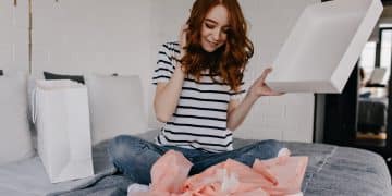 garota sonhadora em camiseta listrada sentada na cama mulher encaracolada ruiva em extase posando no quarto